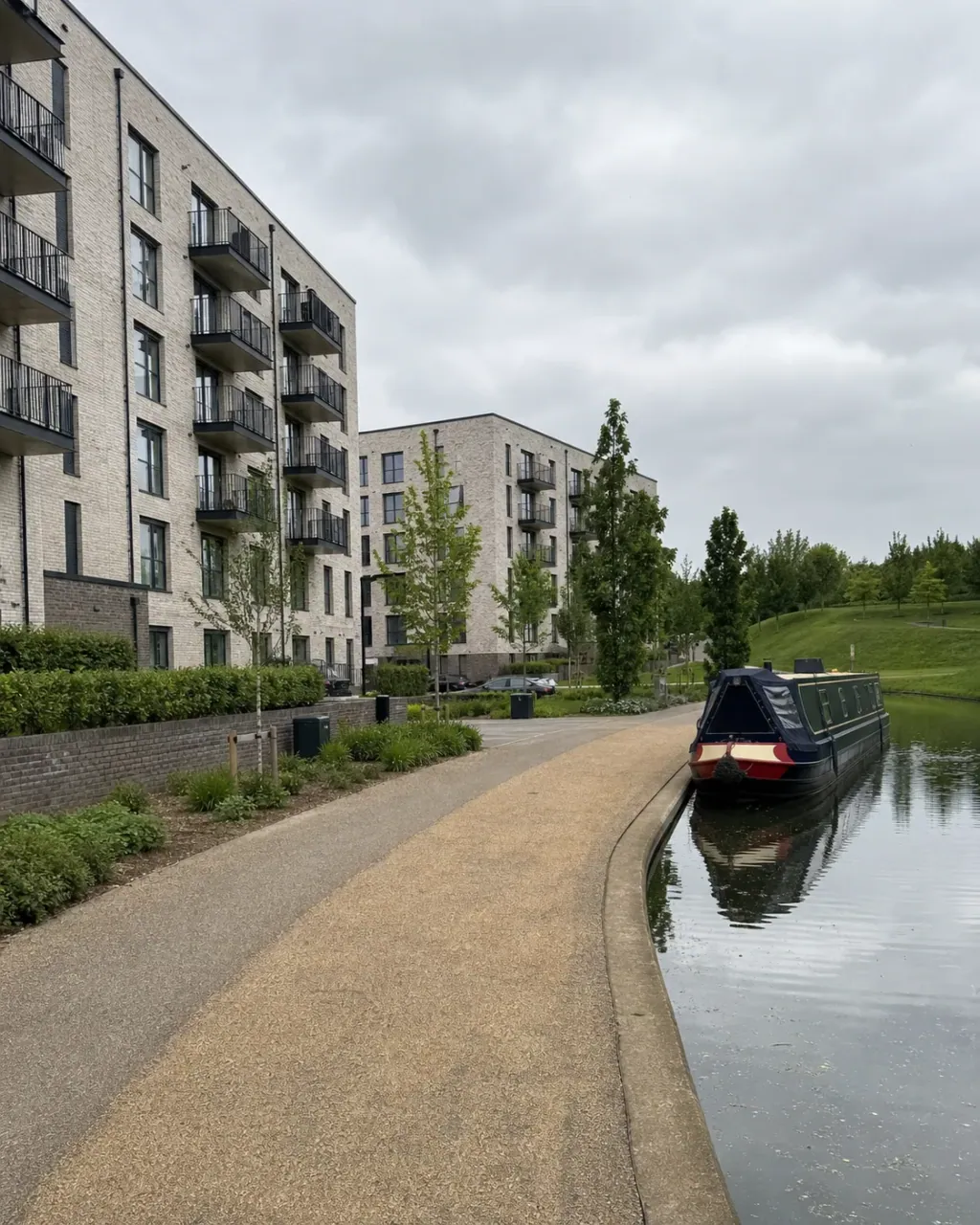 Contemporary canalside apartment buildings at Campbell Park, with a moored narrowboat on the water, a towpath and new landscaping alongside open parkland