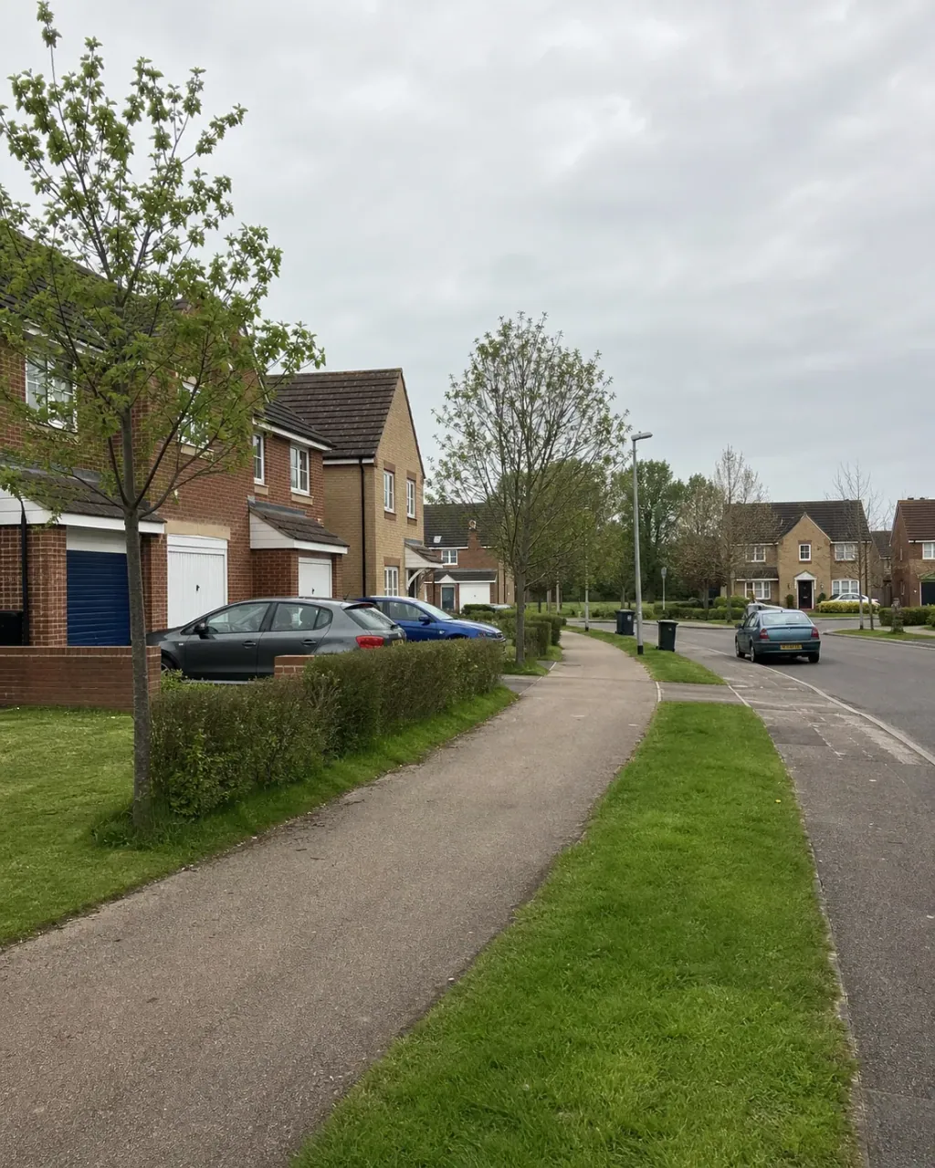 A Monkston estate street of brick houses with garages, wide grass verges and a tarmac redway cycle path curving away between planted banks
