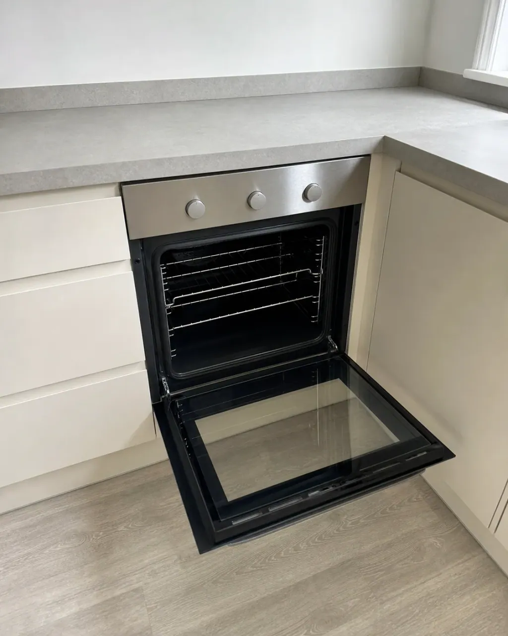 An open oven door in a modern Milton Keynes fitted kitchen showing a completely clean empty cavity with the inner glass clear